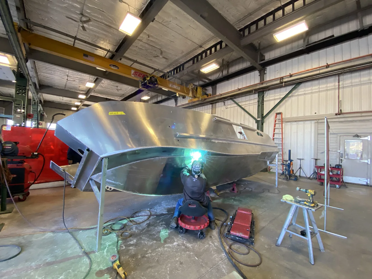 A worker beneath an unfinished boat hull in the workshop