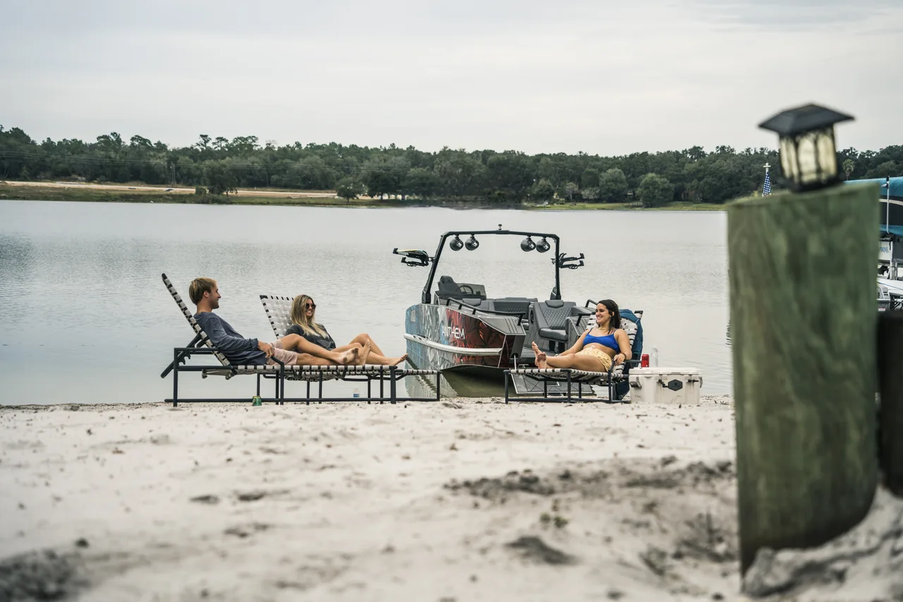 Guests relaxing beside an Anthem boat on a sandy shore